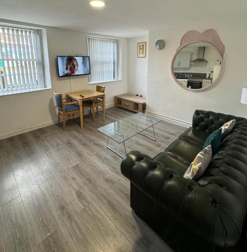a living room with a black leather couch and a table at Westgate Apartments in Newcastle upon Tyne