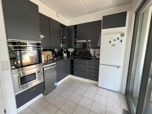 a kitchen with gray cabinets and a white refrigerator at ꕥ Oceanfront Modern Apartment ꕥ in Helsinki