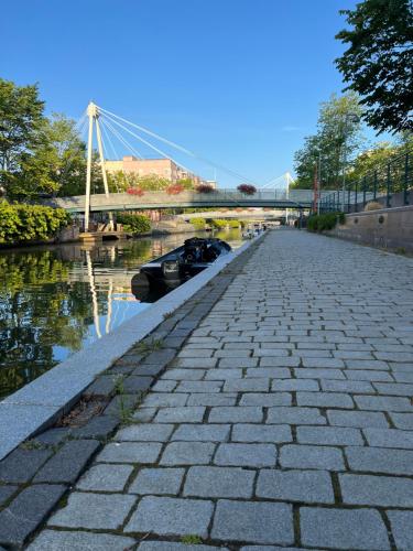 a stone walkway next to a river with a bridge at ꕥ Oceanfront Modern Apartment ꕥ in Helsinki