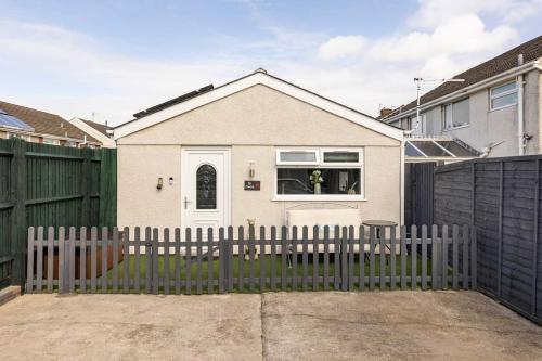a white house with a fence in front of it at Ty Cwtch in Nottage