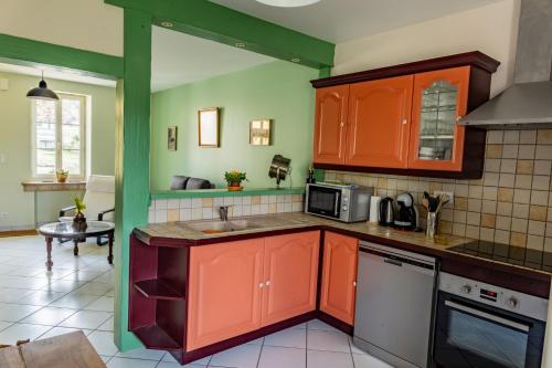 a kitchen with orange cabinets and a sink at Gîte Le Vieux Chêne in Lhuis