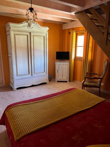 a bedroom with a bed and a cabinet and a television at La Grange de Félix in Fontainebrux
