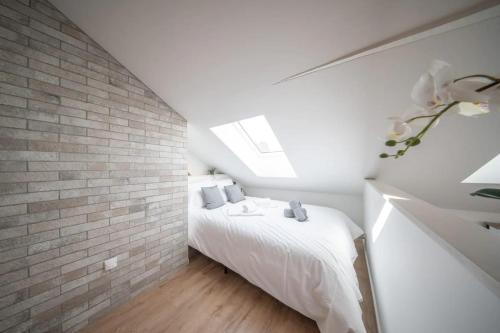 - une chambre blanche avec un mur en briques dans l'établissement Superbe appartement climatisé parking free, à Mulhouse