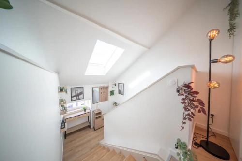 un couloir mansardé avec des murs blancs et une lucarne dans l'établissement Superbe appartement climatisé parking free, à Mulhouse