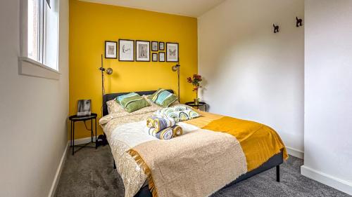 a bedroom with a bed with a yellow wall at Quite Charming house near Glasgow in Clydebank