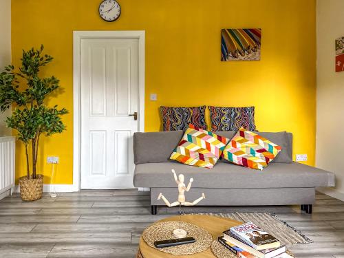 a living room with a gray couch and a yellow wall at Quite Charming house near Glasgow in Clydebank