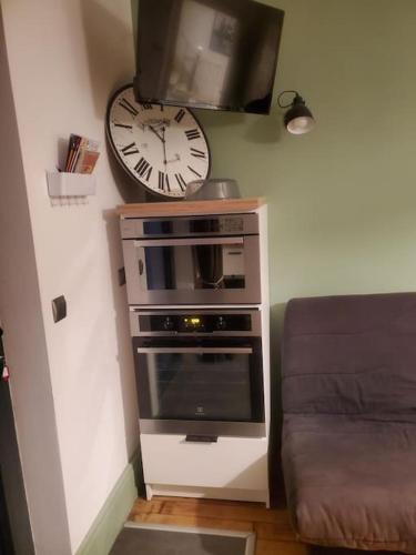 une horloge murale au-dessus d'une cuisinière et d'un micro-ondes dans l'établissement Le courpata, à Bougé-Chambalud