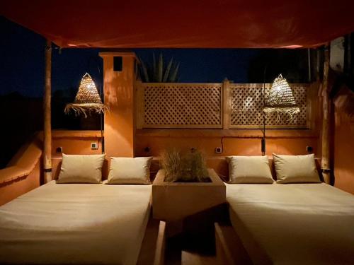 a couple of beds in a room with lights at Dar Akal in Marrakech