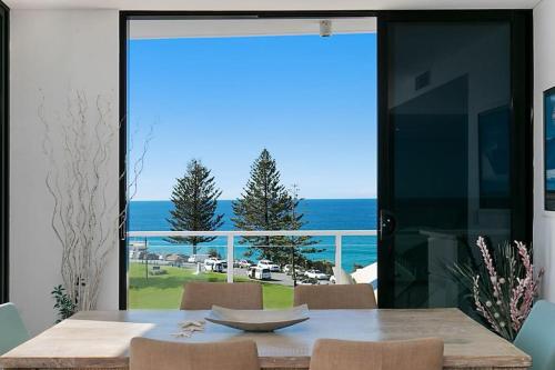 a dining room with a table and a view of the ocean at Living The Dream Penthouse in Tweed Heads
