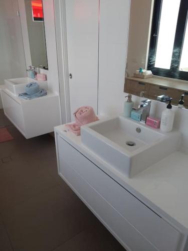 a white bathroom with a sink and a mirror at Living The Dream Penthouse in Tweed Heads