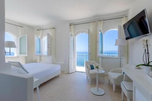 a white bedroom with a bed and a balcony at Relais La Ghinghetta in Portoscuso