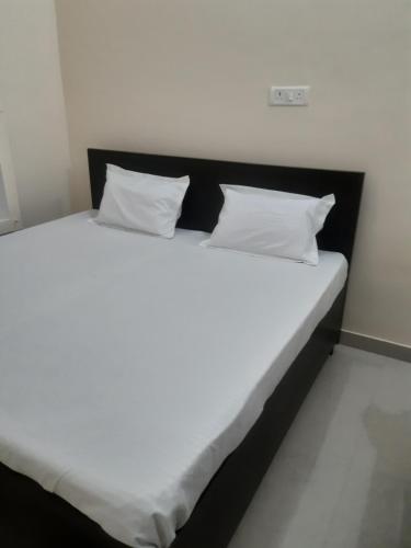 a large bed with white sheets and pillows at Shri Ramesht paying Guest House in Ayodhya