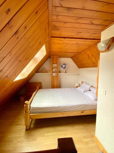 Ce lit se trouve dans un dortoir doté de plafonds en bois. dans l'établissement Appartement Chalet à 1400m - Station du Mourtis, à Boutx
