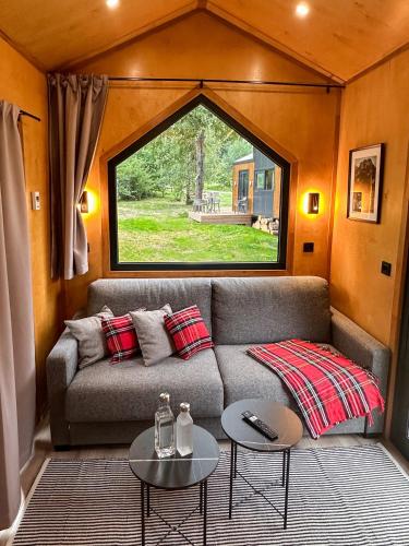 a living room with a couch and a large window at ARIETES MARMONT Tiny Houses in Štrbské Pleso