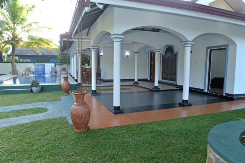 a house with columns and a courtyard with a yard at Sri Ra'anana Villa in Marawila