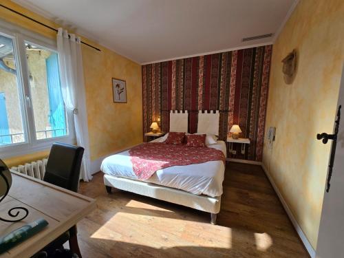 a bedroom with a bed and a table and a desk at Logis Hôtels Le Saint Marc in Mollans-sur-Ouvèze
