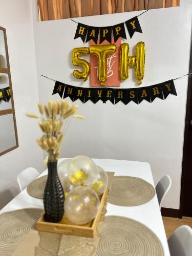 a table with a happy anniversary sign and a vase of balloons at 2BR Condo for Rent near Highway in Marilao