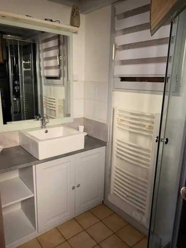 une salle de bain blanche avec un lavabo et un miroir dans l'établissement Chalet paisible et familial, à Gujan-Mestras