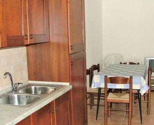 Una cocina con fregadero y una mesa con sillas. en Villaloddo 3 Marina di Tertenia cap 08047 dietro Ristorante La Grotta, en Tertenìa
