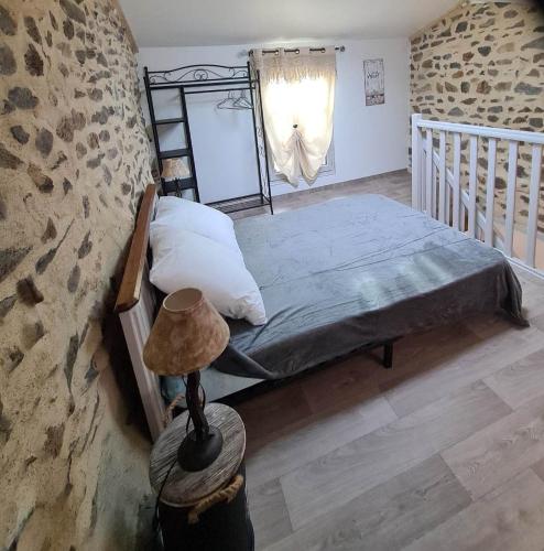 une chambre avec un lit et un mur en pierre dans l'établissement Gite la Fermette 4 à 6 personnes, à Ardes-sur-Couze