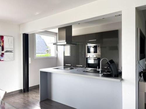 - une cuisine avec un comptoir blanc, un évier et un four micro-ondes dans l'établissement Maison avec jardin à 300 m de la mer, à Saint-Pierre-Quiberon