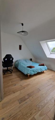- une chambre avec un lit et une chaise sur du parquet dans l'établissement Fare-Kermenezy maison avec piscine chauffée, à Locmaria-Grand-Champ