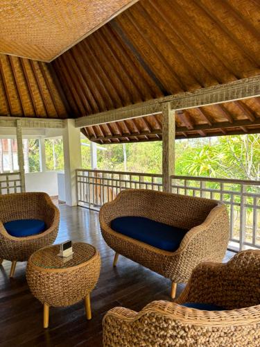 a porch with wicker chairs and a table at Private Villa Kayu Padangbai in Padangbai