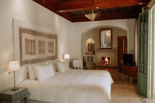 a bedroom with a large white bed and a fireplace at Les Deux Tours in Marrakech
