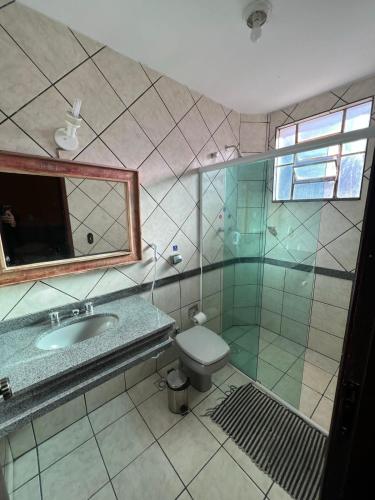 a bathroom with a sink and a toilet and a mirror at Pousada Aconchego de Minas in Juiz de Fora
