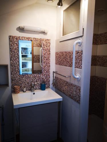une salle de bain avec un lavabo et un miroir dans l'établissement Chambres avec salle de bains et cuisine en centre ville Argenton sur Creuse, à Argenton-sur-Creuse