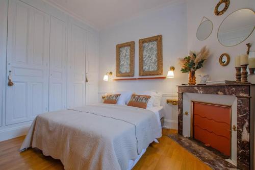 a bedroom with a white bed and a fireplace at La Maison D'Othe in Estissac