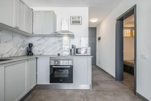 a kitchen with white cabinets and a stove top oven at Patalavaca Beach, One Bedroom Apartment in Patalavaca