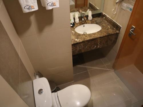 a bathroom with a white toilet and a sink at Al Mukhtara Plaza Hotel - فندق المختارة بلازا in Medina