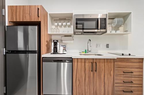 a kitchen with a stainless steel refrigerator and a microwave at Hawthorn Extended Stay by Wyndham Port Arthur in Port Arthur