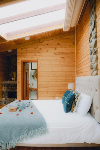 a bedroom with a large white bed with wooden walls at The Cottage Angochagua in Ibarra
