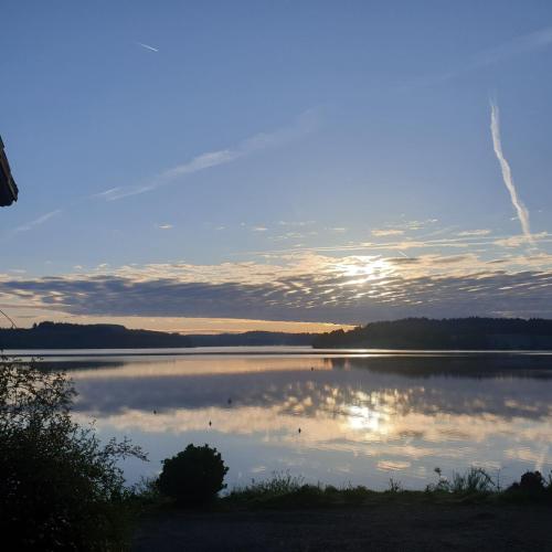 a view of a lake with the sun reflecting on the water at Hotel Restaurant La Caravelle in Peyrat-le-Château