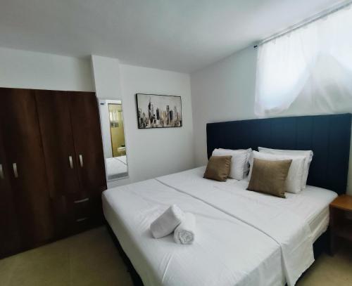 a bedroom with a large white bed with a blue headboard at Suite Hermosa ven descansa o trabaja El Rodadero 50m Playa in Gaira