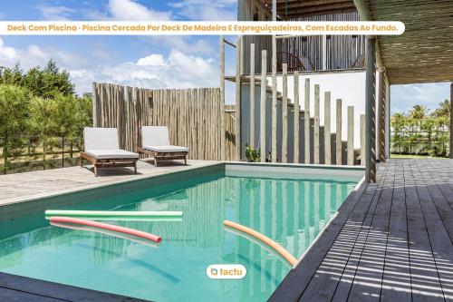 a swimming pool with two chairs and a house at Casa Pipa em condomínio de luxo no Fortim in Barra (2)