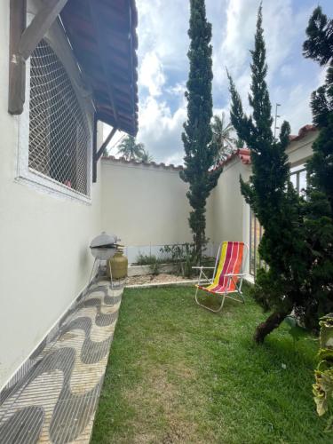 Un patio trasero con una cerca, una silla y árboles. en Casa Pet Friendly, en Guarapari