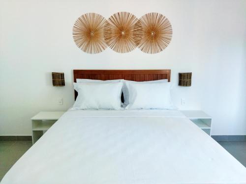 a bedroom with a large white bed and two mirrors at Pousada Fenícia in Japaratinga