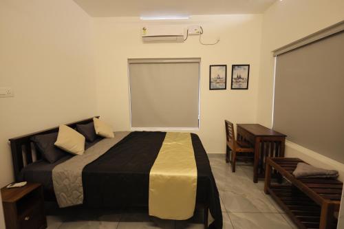 a bedroom with a bed and a desk and a window at INDIGO Springs in Trivandrum