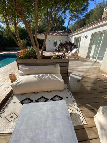 Un patio con mesa y almohadas junto a una piscina. en villa Bikini Bormes les mimosas, en Bormes-les-Mimosas