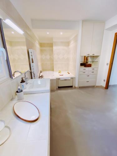 La salle de bains blanche est pourvue d'un lavabo et d'une baignoire. dans l'établissement villa Bikini Bormes les mimosas, à Bormes-les-Mimosas