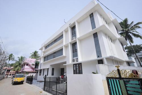 a white building with a car parked in front of it at INDIGO Springs in Trivandrum