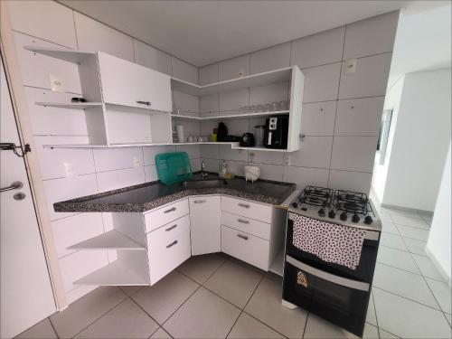 レシフェにあるConfortável apartamento com 2 quartos, sendo um suíte, varanda, ampla sala, cozinha área de serviço e banheiro socialの白いキッチン(白いキャビネット、コンロ付)