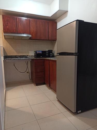 a kitchen with a black refrigerator and wooden cabinets at Apartamento en Ciudad Juan Bosch in La Javilla