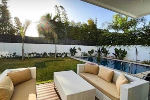 a living room with a couch and a pool at Poolside Paradise Villa in Dar Ben Abdallah Ben Dehbi