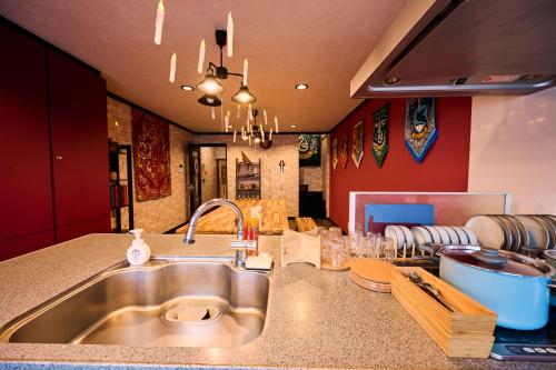 a kitchen with a stainless steel sink and red walls at Harry Potter Osaka HogwartsSchool哈利波特 魔法学院 in Osaka