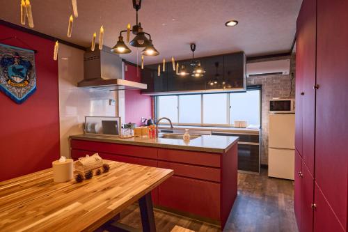 a kitchen with red cabinets and a wooden table at Harry Potter Osaka HogwartsSchool哈利波特 魔法学院 in Osaka