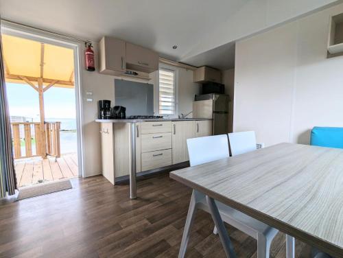 une cuisine et une salle à manger avec une table et des chaises dans l'établissement Mobil home 5 personnes vue mer, à Tihen